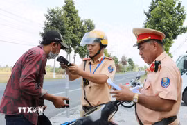 Cảnh sát giao thông kiểm tra nồng độ cồn. (Ảnh minh họa. Văn Sĩ/TTXVN)