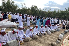 Con, cháu dòng tộc theo đạo Hồi giáo Bàni mặc bộ áo truyền thống thực hiện nghi lễ tảo mộ tại nghĩa trang, mời tổ tiên về chung vui Tết Ramưvan. (Ảnh: Công Thử/TTXVN)