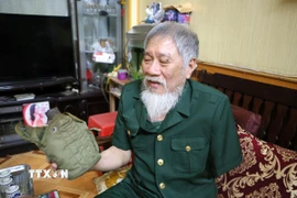 Ông Nguyễn Thế Tám nâng niu chiến tích tịch thu được của quân địch trong thời gian tham gia giải phóng Sài Gòn. (Ảnh: Công Luật/TTXVN)
