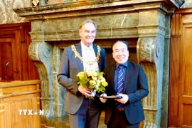 Ông Burkhard Jung, Thị trưởng thành phố Leipzig trao tặng huy hiệu, bảng vàng danh dự, bằng khen của Thành phố Leipzig cho ông Bùi Quang Huy - Chủ tịch Hội người Việt tại thành phố Leipzig. (Ảnh: Phương Hoa/TTXVN)