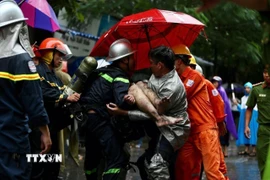 Lực lượng cứu hỏa đưa nạn nhân cuối cùng ra khỏi đám cháy tòa nhà 5 tầng ở số 8, ngõ 12, phố Núi Trúc, quận Ba Đình, Hà Nội. (Ảnh: Dương Giang/TTXVN)