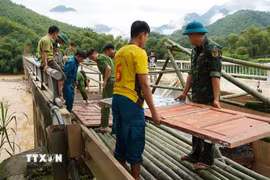 Người dân và chính quyền đã kịp thời khắc phục sự cố đầu Cầu Sơn Thủy trên Quốc lộ 16 tại lý trình Km89+580 tại bản Chung Sơn bị hư hỏng nặng chân, mố cầu, và bị sập hoàn toàn mặt đường nhựa dài hơn 10 mét. (Ảnh: TTXVN phát)