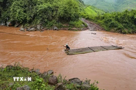 Đi bè tre qua suối lũ luôn tiềm ẩn nguy hiểm. (Ảnh: Xuân Tư/TTXVN)