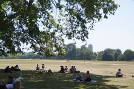 Người dân tránh nóng dưới bóng cây trong công viên ở London, Anh. (Ảnh: THX/TTXVN)