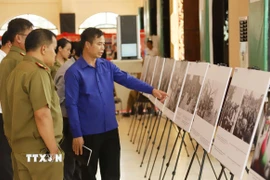 Cán bộ Đoàn và sỹ quan công an Lào tham quan khu trưng bày ảnh về Chiến dịch Hồ Chí Minh lịch sử của Việt Nam. (Ảnh: Xuân Tú/TTXVN)