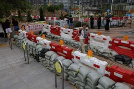 Người dân đi ngang qua những bao cát được đặt để ngăn lũ lụt do siêu bão Ragasa gây ra. (Nguồn: Reuters)