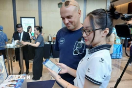 Giới thiệu phần mềm ứng dụng ví điện tử du lịch thông minh đến du khách quốc tế. (Ảnh: Mỹ Hà/TTXVN)