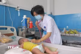 Bác sỹ Bệnh viện Bệnh Nhiệt đới Thành phố Hồ Chí Minh khám cho bệnh nhi mắc sởi. (Ảnh: Đinh Hằng/TTXVN)