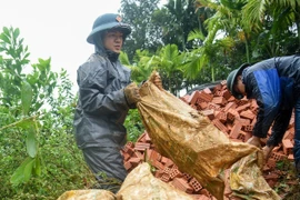Cán bộ, chiến Ban Chỉ huy Phòng thủ Khu vực 5-Điện Bàn (Bộ Chỉ huy Quân sự thành phố Đà Nẵng) vận chuyển vật liệu xây dựng nhà cho bà con xã Trà Leng. (Ảnh: Quốc Dũng/TTXVN)