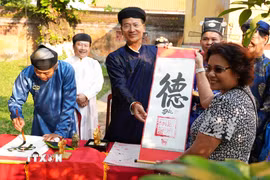 Du khách được tặng chữ thư pháp đầu năm mới Bính Ngọ ở Thế Miếu, Đại Nội Huế. (Ảnh: Nguyên Lý/TTXVN)