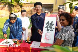 Du khách được tặng chữ thư pháp đầu năm mới Bính Ngọ ở Thế Miếu, Đại Nội Huế. (Ảnh: Nguyên Lý/TTXVN)