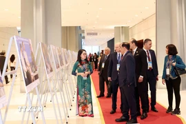 Đại biểu quốc tế tham quan trưng bày ảnh của Thông tấn xã Việt Nam tại Lễ mở ký Công ước Hà Nội, sáng 25/10. (Ảnh: Phương Hoa/TTXVN)