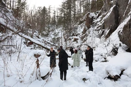 Du khách thích thú chụp ảnh dưới chân Trường Bạch Sơn. (Ảnh: Quang Hưng/TTXVN)