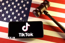 Logo của ứng dụng TikTok trên điện thoại và quốc kỳ Mỹ. (Ảnh: Reuters/TTXVN)\