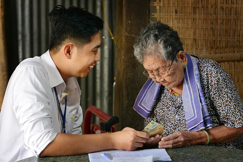 Cán bộ bưu điện chi trả lương hưu, trợ cấp tại nhà cho người già yếu không có khả năng đến nhận. (Ảnh: CTV/Vietnam+)