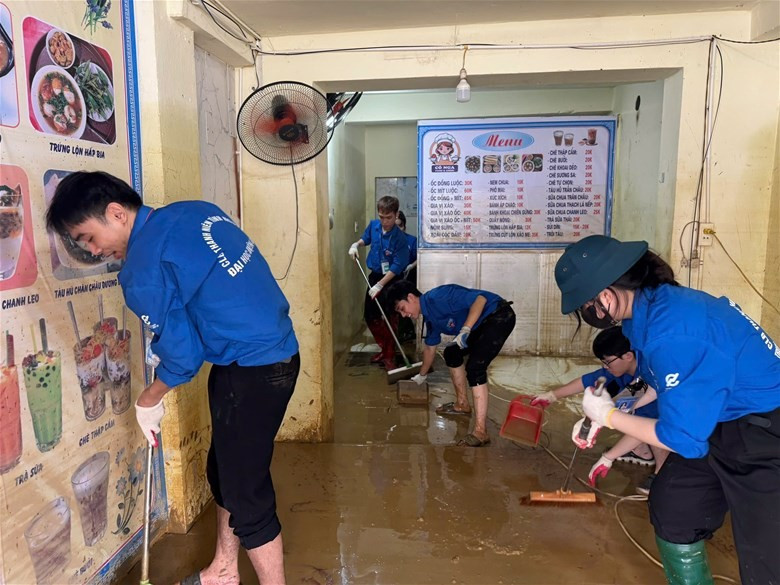 Thanh niên tình nguyện trường Đại học Điện lực dọn dẹp bùn đất sau bão lũ cho người dân. (Ảnh: Trường Đại học Điện lực)