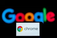 Biểu tượng Chrome trên màn hình điện thoại và biểu tượng Google (phía sau). (Ảnh: Getty Images/TTXVN)