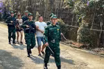 Bội đội biên phòng áp giải 2 đối tượng mua bán người trong chuyên án. (Ảnh: TTXVN phát)