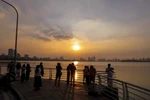 Nhiều người dân lưu lại khoảnh khắc với vẻ đẹp của hoàng hôn Hồ Tây. (Ảnh: Khánh Hòa/TTXVN)