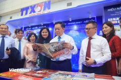 Ông Nguyễn Trọng Nghĩa, Ủy viên Bộ Chính trị, Bí thư Trung ương Đảng, Trưởng Ban Tuyên giáo và Dân vận Trung ương cùng các đại biểu tham quan gian trưng bày của Thông tấn xã Việt Nam tại Hội báo. (Ảnh: Hoài Nam/TTXVN)