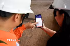 Công nhân (EVNHANOI) hướng dẫn khách hàng sử dụng Ứng dụng EVNHANOI trên website evnhanoi.vn. (Ảnh: Quốc Lũy/TTXVN)
