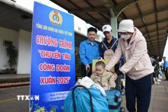 Cán bộ công đoàn tại Đồng Nai hỗ trợ người lao động vận chuyển hành lý và chuẩn bị lên tàu về quê đón Tết. (Ảnh: Lê Xuân/TTXVN)