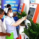 Nhân viên y tế hướng dẫn người dân đăng ký khám bệnh qua hệ thống kios tự động tại Bệnh viện Đa khoa Trà Vinh, tỉnh Vĩnh Long. (Ảnh: TTXVN)