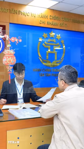 Cán bộ, công chức Trung tâm Phục vụ hành chính công thành phố Hà Nội-Chi nhánh số 3 hướng dẫn người dân hoàn thiện hồ sơ thủ tục hành chính. (Ảnh: TTXVN phát)