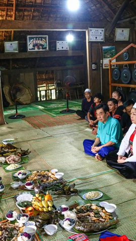Trong lễ cúng vía bếp của người Mường, con cháu trong nhà ngồi quây quần thực hiện nghi lễ. (Ảnh: Hải Ly/TTXVN)