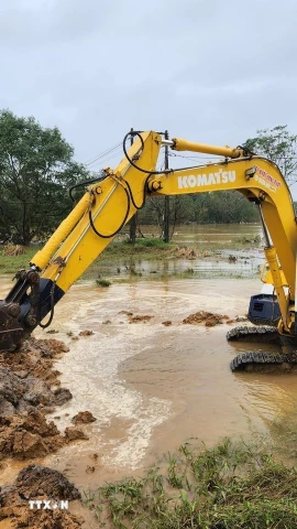 Đắp đất làm đê tạm, ngăn dòng nước chảy xiết tiếp tục gây xói lở phần đất, đá gia cố trên đoạn đê. (Ảnh: Mai Trang/TTXVN)
