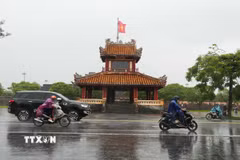 Các phương tiện di chuyển trong mưa lớn ở trước di tích Phu Văn Lâu, trung tâm thành phố Huế. (Ảnh: Nguyên Lý/TTXVN)
