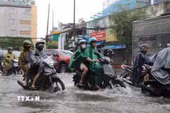 Người dân di chuyển qua đoạn đường Đinh Bộ Lĩnh, phường Bình Thạnh bị ngập do cơn mưa chiều 23/9. (Ảnh: Hồng Đạt/TTXVN)