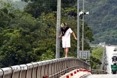 Hình ảnh nam thanh niên đứng ở độ cao lớn so với mặt nước, tiềm ẩn nguy cơ trượt chân, rơi xuống sông. (Ảnh: TTXVN phát)