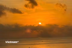 Bầu trời đỏ rực từ từ nhô lên khỏi mặt nước, ánh sáng lan nhanh khắp mặt biển. (Nguồn: Vietnam+)