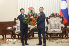 Đại sứ Việt Nam tại Lào Nguyễn Minh Tâm chuyển lẵng hoa chúc mừng của đồng chí Lê Minh Hưng, Ủy viên Bộ Chính trị, Thủ tướng Chính phủ Việt Nam chúc mừng đồng chí Saleumxay Kommasitt, Ủy viên Bộ Chính trị, Thủ tướng Chính phủ Lào. (Ảnh: Xuân Tú/TTXVN)