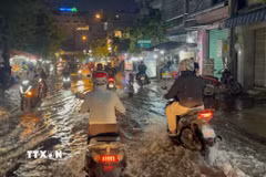 Các phương tiện lưu thông trên đường Trần Xuân Soạn, phường Tân Thuận, bị ngập do triều cường buổi tối 28/9. (Ảnh: Hồng Đạt/TTXVN)