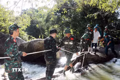 Đội Tìm kiếm, quy tập hài cốt liệt sỹ tỉnh Khánh Hòa vượt cầu tạm để băng suối nước chạy xiết. (Ảnh: Công Thử/TTXVN)
