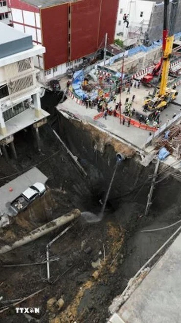 Một đoạn đường trước bệnh viện Vajira đã bất ngờ bị sụt, tạo thành hố lớn có diện tích 30x30m và sâu tới 50m. (Ảnh: Reuters/TTXVN)