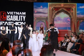 Cặp vợ chồng "tí hon" nhưng truyền cảm hứng mạnh mẽ Nguyễn Văn Hùng và Lê Thị Diễm My (đều 37 tuổi) cùng các nhà tạo mẫu của chương trình. Anh chị được thiết kế trang phục trắng muốt tinh khôi, nổi bật trên sàn diễn. (Ảnh: Minh Anh/Vietnam+)