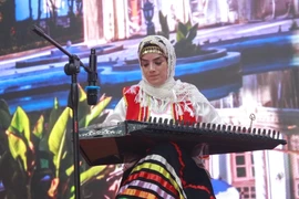 Nghệ sỹ ban nhạc Sar Afshan trình diễn với đàn Qanun, một nhạc cụ truyền thống của Iran có nhiều điểm tương đồng với đàn Tam thập lục tại Việt Nam. (Ảnh: Minh Anh/Vietnam+)