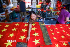 Người thợ kiểm tra lại từng sản phẩm, chỉnh sửa những chi tiết nhỏ nhất để đảm bảo mỗi lá cờ đều đạt chuẩn. (Ảnh: Lê Ngọc/TTXVN phát)