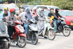 Khẩu trang, áo chống nắng là những thứ không thể thiếu của người dân khi tham gia giao thông. (Ảnh: Lê Đông/TTXVN)