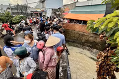 Nhiều người dân hiếu kỳ đứng xem lực lượng chức năng tìm kiếm tại đoạn suối nơi bé gái bị nước cuốn mất tích. (Ảnh: Lê Xuân/TTXVN)