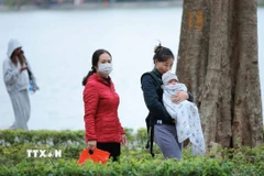 Trẻ nhỏ được che chắn kỹ chống rét khi phải di chuyển ngoài trời. (Ảnh: Hoàng Hiếu/TTXVN)