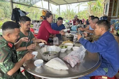 Chiến sỹ Quân khu 5 cùng người dân xã Hòa Thịnh ăn uống, nghỉ ngơi sau một ngày làm việc vất vả. (Ảnh: Tường Quân/TTXVN)