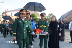 Các đại biểu thực hiện di quách đưa hài cốt liệt sỹ về với đất mẹ. (Ảnh: Đậu Tất Thành/TTXVN)
