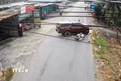 Tài xế bất chấp hiệu lệnh, điều khiển ôtô húc ngang chiếc mô tô của Cảnh sát giao thông, khiến phương tiện ngã xuống đường. (Ảnh: TTXVN phát)