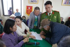 Người dân kí nhận, làm thủ tục để nhận quà của Đảng và Nhà nước. (Ảnh: Thanh Thuỷ/TTXVN)