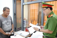 Cơ quan Cảnh sát điều tra Công an tỉnh An Giang tống đạt các Quyết định và Lệnh đối với bị can Đặng Cửu Quí. (Ảnh: TTXVN phát)