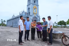 Cán bộ xóm 2, xã Nghĩa Sơn tới nhà thờ trên địa bàn để tuyên truyền, vận động người dân đồng thuận với chủ trương sắp xếp, tổ chức lại thôn, tổ dân phố. (Ảnh: Công Luật/TTXVN)